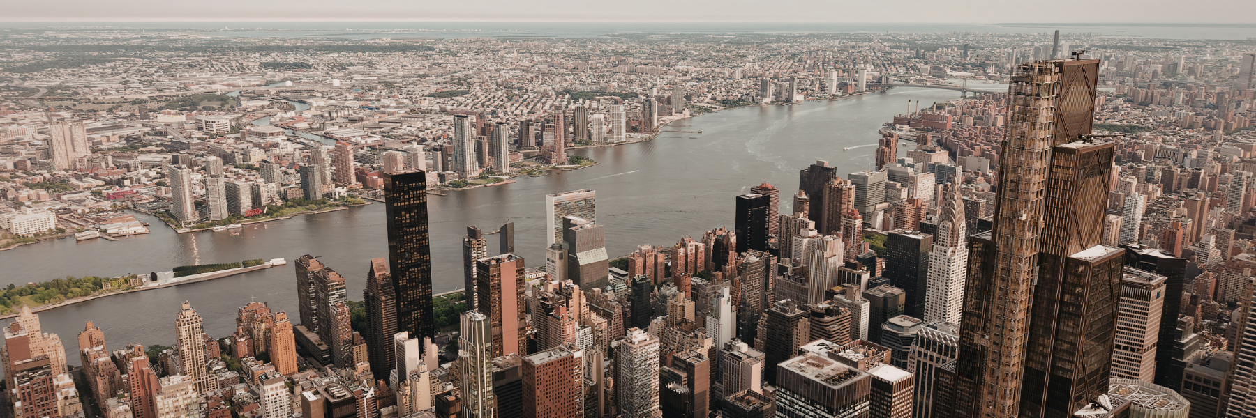 Flat commercial roof with HVAC units and roof penetrations in a dense urban environment