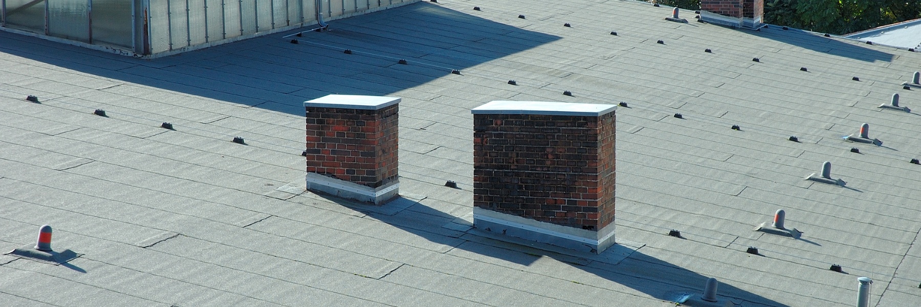 Flat commercial roof with penetrations where wet insulation can impact commercial roof repair replacement decisions